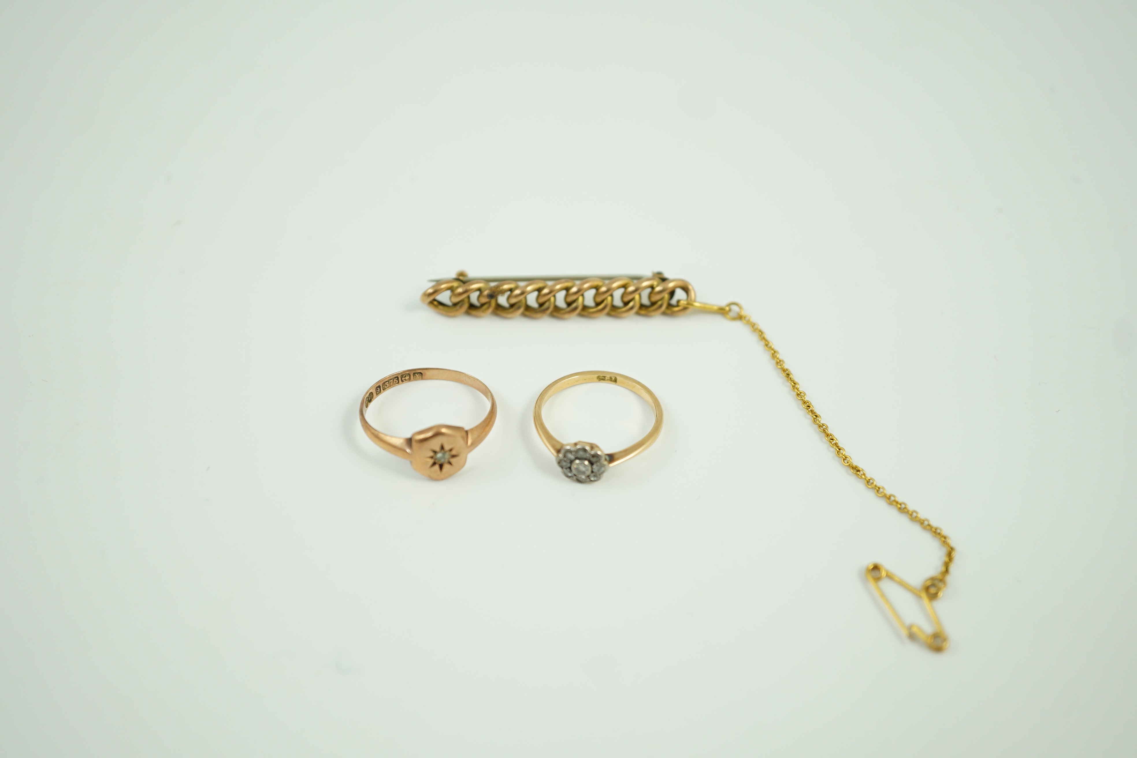 A small 18ct and diamond set cluster ring, size K, gross 1.2 grams, a 9ct gold and diamond chip set ring and a yellow metal curb link bar brooch, gross 5.1 grams.